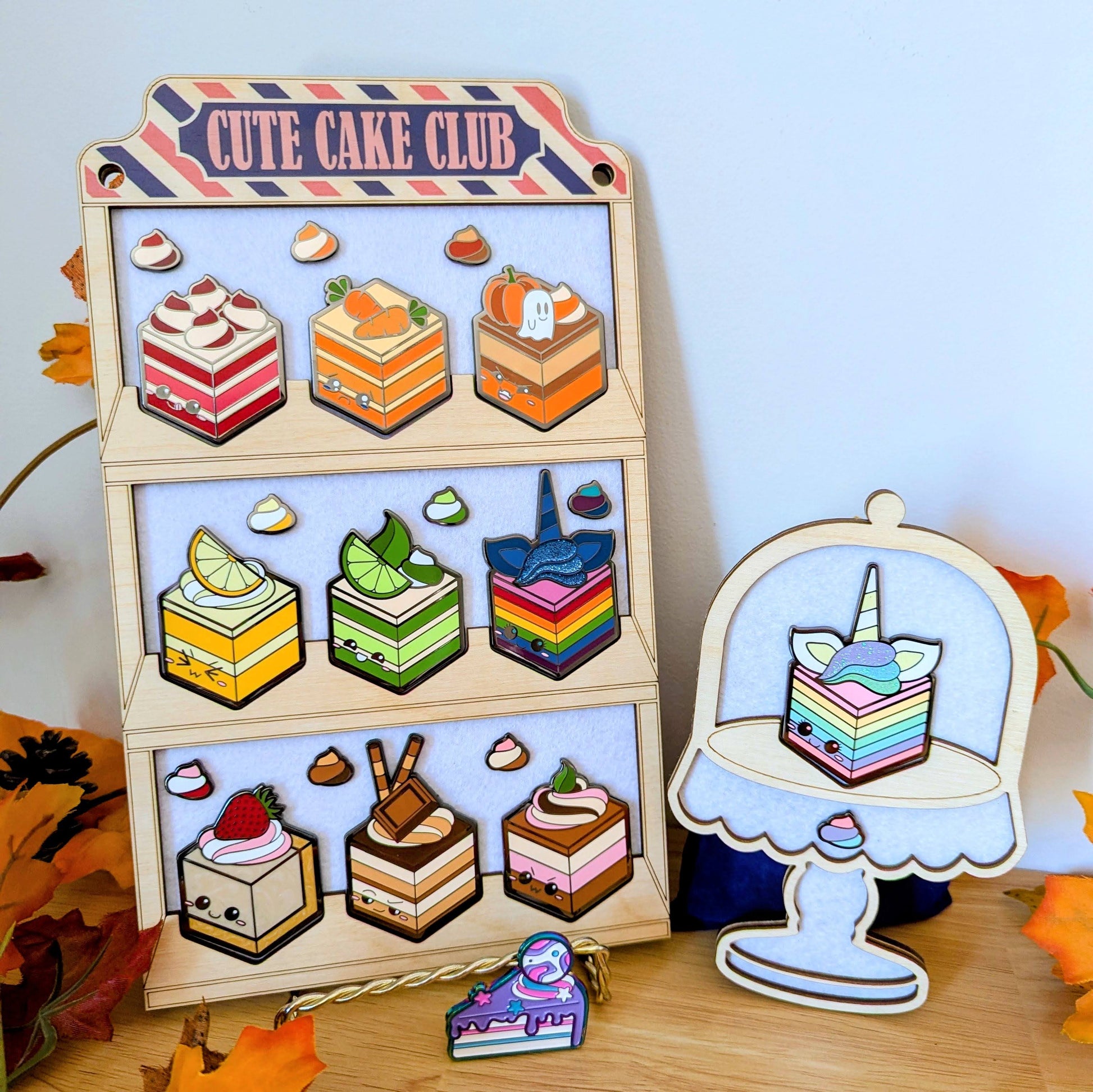 wooden display with cake and dollop enamel pins from cute cake club by carly k of mythic mgmt